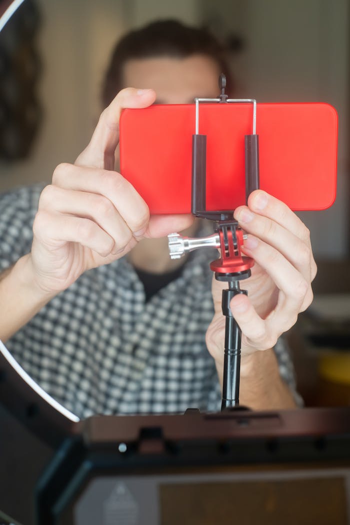 A Person Holding a Smartphone on a Tripod